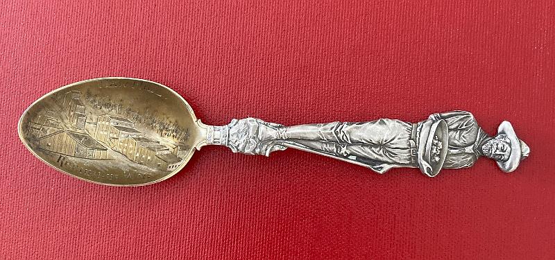 IMG_2113.JPG - SOUVENIR MINING SPOON REPUBLIC MILL REPUBLIC WA Sterling silver spoon, 5 5/8 in. long, engraved mining scene in gold washed bowl, bowl marked NEW MILL REPUBLIC WN (WN changed to WA postal code for Washington state), handle features an ornate image of a full figure of a miner holding a gold pan with gold nuggets, bottom of handle features LUCKY STRIKE on a banner, back of handle features the reverse full image of the miner and marked Sterling with Mayer Bros. makers mark, weight 30.2 gms. [According to the USGS, the Republic district in Ferry County Washington has had the most consistent record of large gold production of any district in the state. The story of the district's mines starts in the 1890s. Ore deposits were first recognized in the area as early as 1893, however much of the land was within the boundaries of the Colville Indian Reservation which was off limits to mining. This changed in 1896 when much of the northern part of the reservation was opened to mining by the government. By spring of that year, the settlement of Eureka contained a small number of canvas buildings and around 60 residents. By summer of 1896 a rush was on to Eureka and hundreds of new residents poured into the new camp. In 1897 the town name was changed to Republic and a post office was established. Although there was much excitement and optimism about the Republic mines in the late 1890s, by 1900 reality had set in and the district hit hard times. Most of the mines yielded only low-grade ore, much of which was exhausted after a short time. The biggest challenge the district faced was the lack of transportation infrastructure.  As a result of these difficulties, the mines of the district shut down in 1901. However by 1903 the railroad arrived at Republic, solving the transportation issue.  Mines were consolidated and ore treatment processes were improved, resulting in steady production of low grade ore for years to come. In 1909 the discovery of substantial amounts of high-grade ore at the Republic mine and of new ore bodies on other properties resulted in a revival of the district; later large-scale production from the Lone Pine and Knob Hill mines sustained activity through 1928. Mining fluctuated from 1928 until after World War II, when the Knob Hill mine emerged as the largest and most consistent producer. In 1960 it was the third most productive lode-gold mine in the United States. Today Republic is still an active town of over 1,000 people with a continuing history of gold mining.]