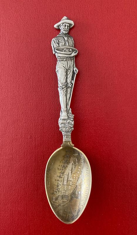 IMG_2114.JPG - SOUVENIR MINING SPOON REPUBLIC MILL REPUBLIC WA Sterling silver spoon, 5 5/8 in. long, engraved mining scene in gold washed bowl, bowl marked NEW MILL REPUBLIC WN (WN changed to WA postal code for Washington state), handle features an ornate image of a full figure of a miner holding a gold pan with gold nuggets, bottom of handle features LUCKY STRIKE on a banner, back of handle features the reverse full image of the miner and marked Sterling with Mayer Bros. makers mark, weight 30.2 gms. [According to the USGS, the Republic district in Ferry County Washington has had the most consistent record of large gold production of any district in the state. The story of the district's mines starts in the 1890s. Ore deposits were first recognized in the area as early as 1893, however much of the land was within the boundaries of the Colville Indian Reservation which was off limits to mining. This changed in 1896 when much of the northern part of the reservation was opened to mining by the government. By spring of that year, the settlement of Eureka contained a small number of canvas buildings and around 60 residents. By summer of 1896 a rush was on to Eureka and hundreds of new residents poured into the new camp. In 1897 the town name was changed to Republic and a post office was established. Although there was much excitement and optimism about the Republic mines in the late 1890s, by 1900 reality had set in and the district hit hard times. Most of the mines yielded only low-grade ore, much of which was exhausted after a short time. The biggest challenge the district faced was the lack of transportation infrastructure.  As a result of these difficulties, the mines of the district shut down in 1901. However by 1903 the railroad arrived at Republic, solving the transportation issue.  Mines were consolidated and ore treatment processes were improved, resulting in steady production of low grade ore for years to come. In 1909 the discovery of substantial amounts of high-grade ore at the Republic mine and of new ore bodies on other properties resulted in a revival of the district; later large-scale production from the Lone Pine and Knob Hill mines sustained activity through 1928. Mining fluctuated from 1928 until after World War II, when the Knob Hill mine emerged as the largest and most consistent producer. In 1960 it was the third most productive lode-gold mine in the United States. Today Republic is still an active town of over 1,000 people with a continuing history of gold mining.]
